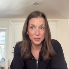 A woman with shoulder-length brown hair speaks animatedly at a kitchen counter, discussing women's r...