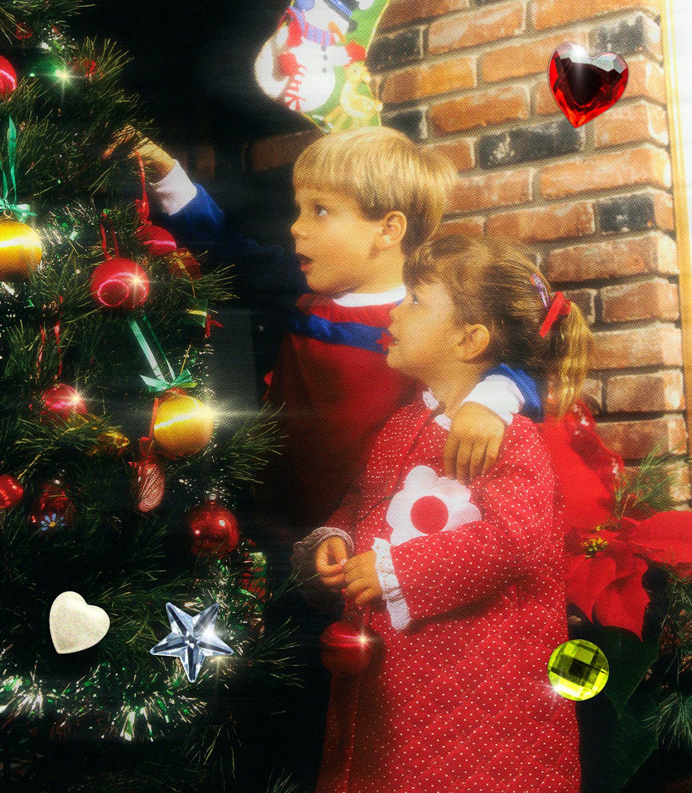 Two children decorate a Christmas tree with colorful ornaments. The background features a cozy brick wall, enhancing the festive atmosphere.