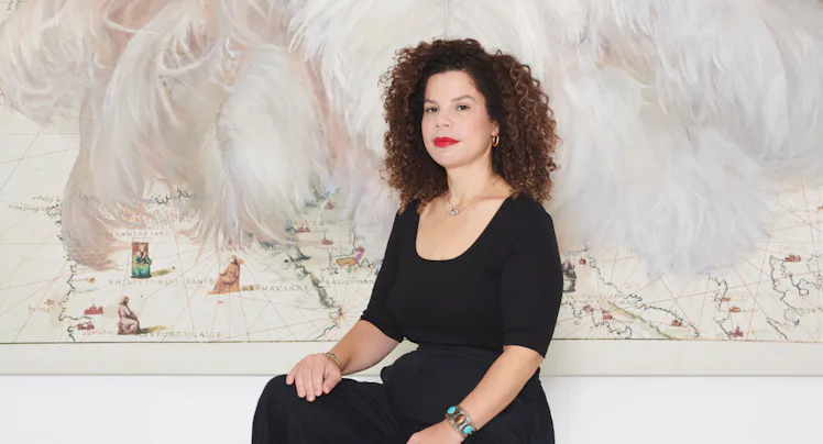 Firelei Báez sitting in front of one of her works