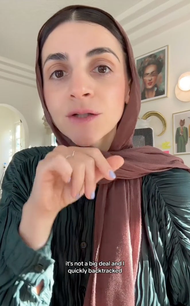 A woman wearing a brown scarf gestures while speaking to the camera. Sunlight streams in, illuminating her expressive face as she discusses a topic.