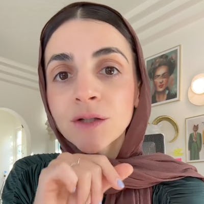 A woman wearing a brown scarf gestures while speaking to the camera. Sunlight streams in, illuminating her expressive face as she discusses a topic.