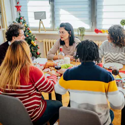 Group of young cheerful friends having Christmas lunch at home