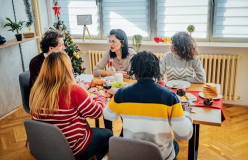 Group of young cheerful friends having Christmas lunch at home