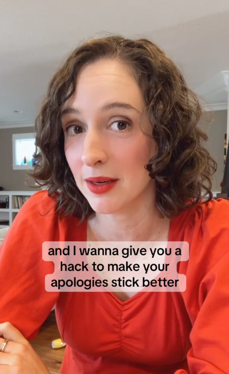 A woman with curly hair and a red top speaks to the camera, sharing tips on making effective apologies. The background is a bright, cozy room.