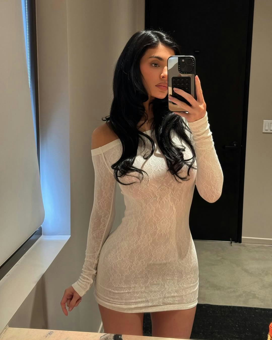 Kylie Jenner wears a lacy white dress.