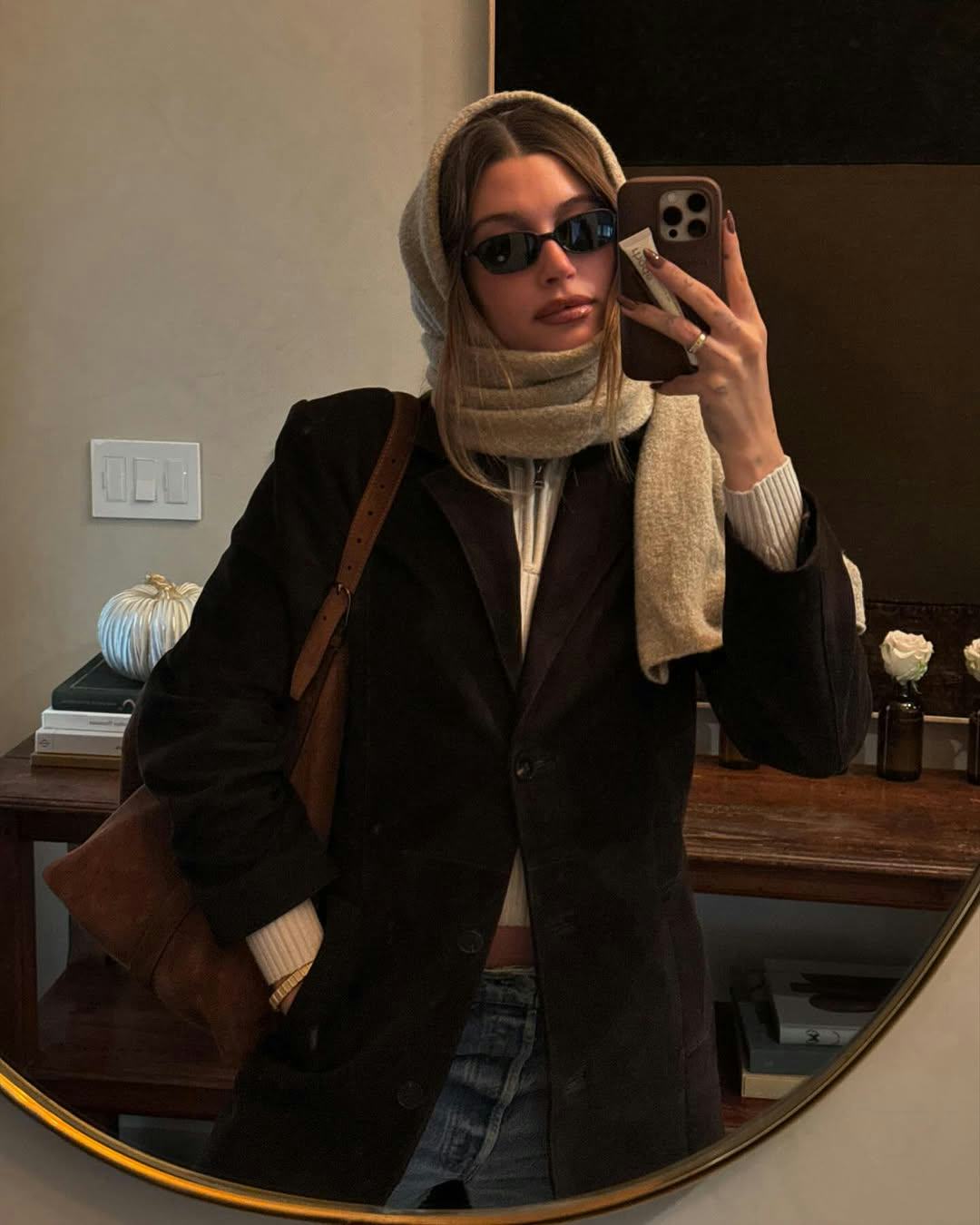 Hailey Bieber wears a crop ribbed top, black coat, and jeans.