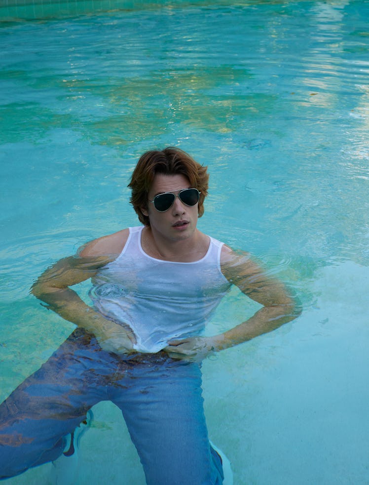 Nicholas Galitzine wears a Calvin Klein tank top; Levi’s jeans; Ray-Ban sunglasses; Nike sneakers.