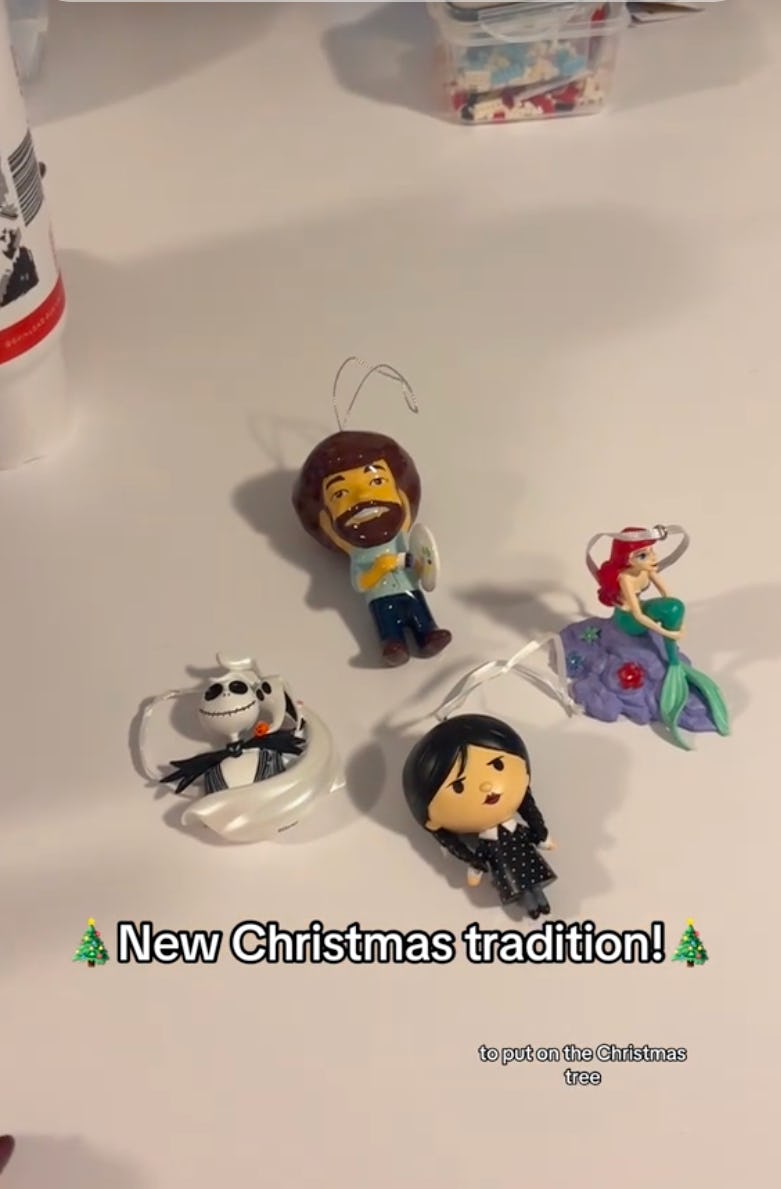 A collection of colorful holiday ornaments featuring a cartoon painter, a mermaid, a skeleton figure, and a character in black clothing, labeled "New Christmas tradition!"