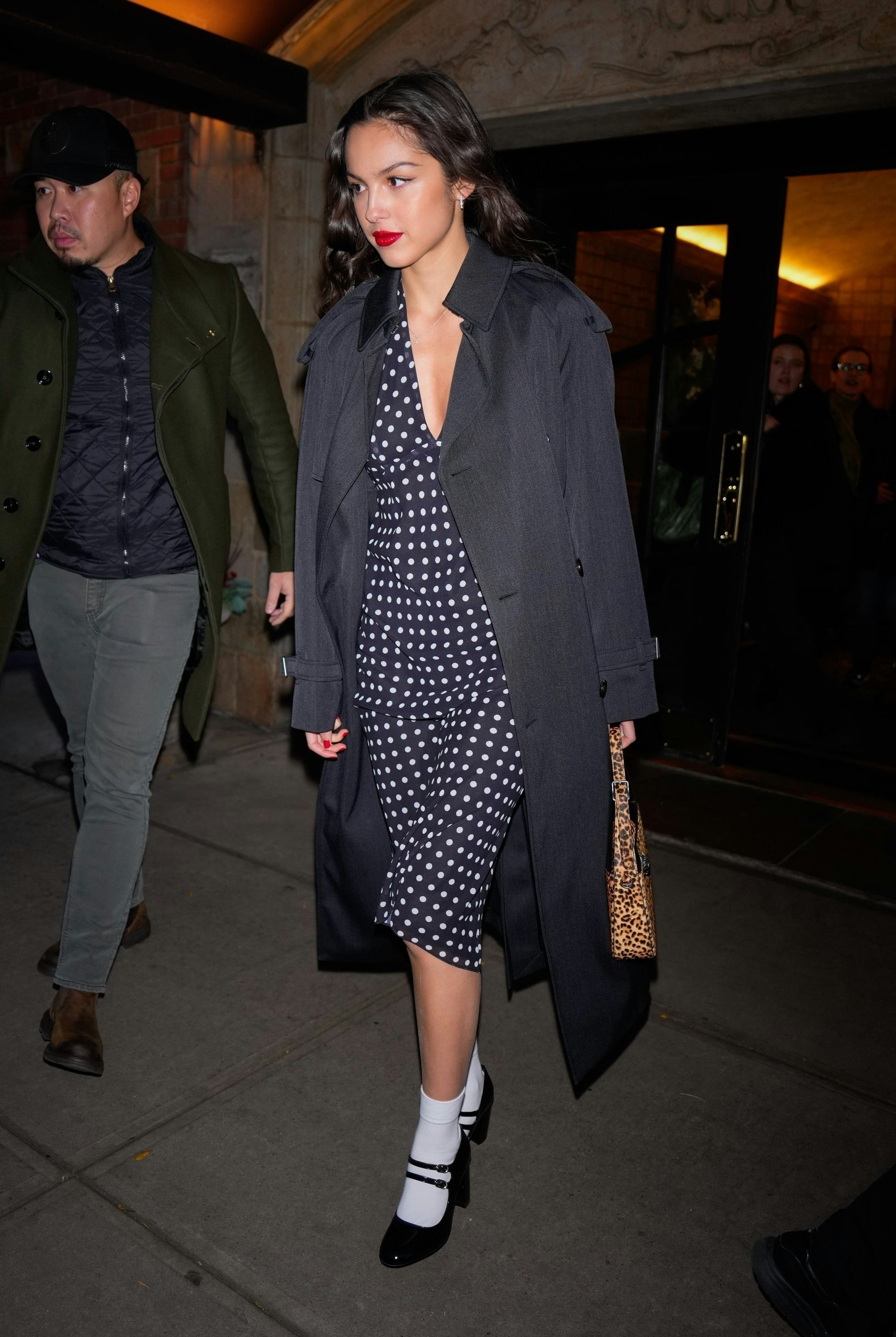 Olivia Rodrigo wears a gray trench over a plunging dotted dress.
