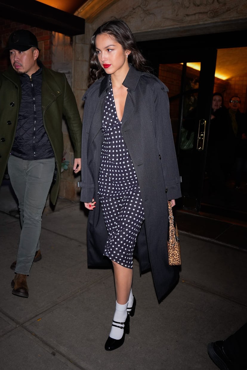 Olivia Rodrigo wears a gray trench over a plunging dotted dress.