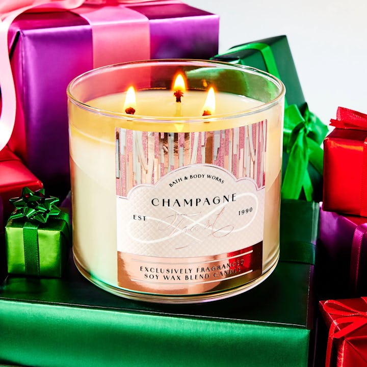 Bath & Body Works champagne toast candle on top of a pile of presents. It's included in this year's ...