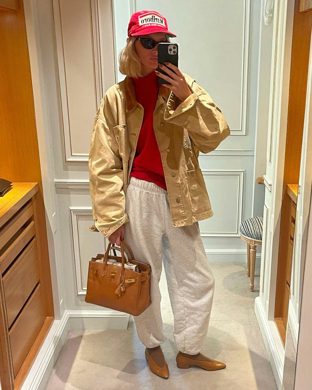 Elsa Hosk wears a red sweater, gray sweatpants, and a Birkin.