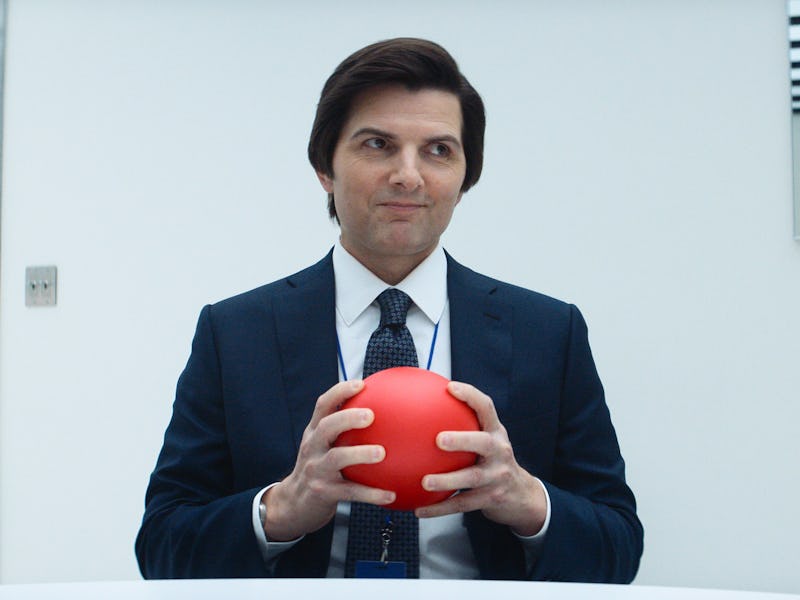 A man in a dark suit sits at a table holding a red ball, with a thoughtful expression. A clock is vi...