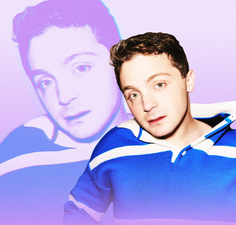 A person with short, curly hair and a blue striped sweater poses against a soft pink background, wit...