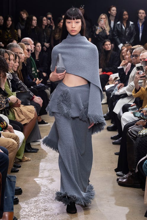 Proenza Schouler model in blue knit asymmetrical top and fringed maxi skirt