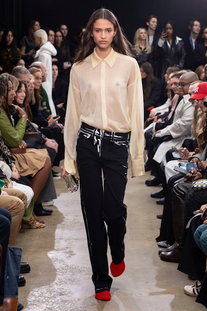 Proenza Schouler model in sheer blouse and white painted black jeans 