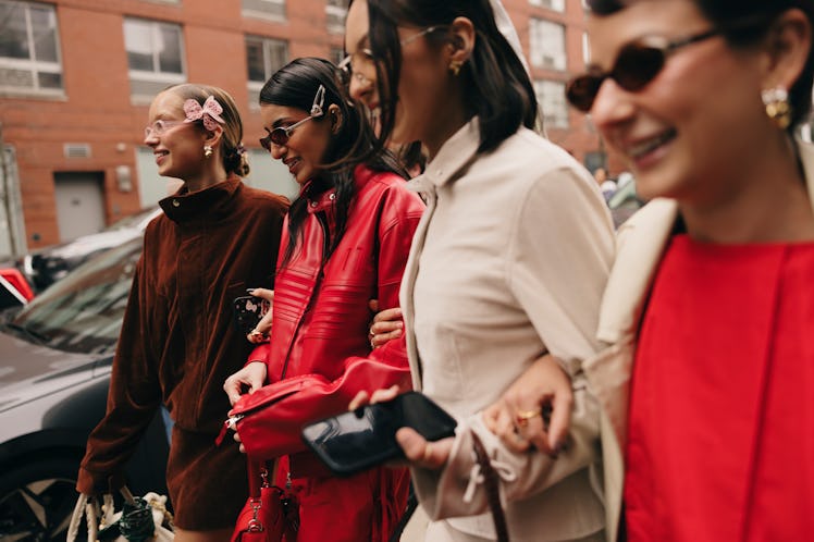 a photo of four people walking arm in arm during fashion week