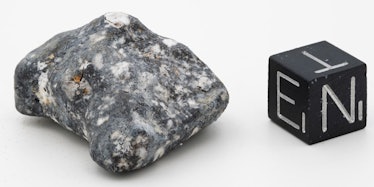 A grainy gray rock sits next to a black block marked with letters E, T, and N