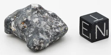 A grainy gray rock sits next to a black block marked with letters E, T, and N