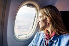 A woman looks out the window of an airplane during her flight.