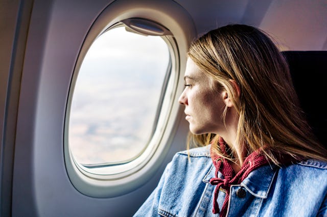 A woman looks out the window of an airplane during her flight.