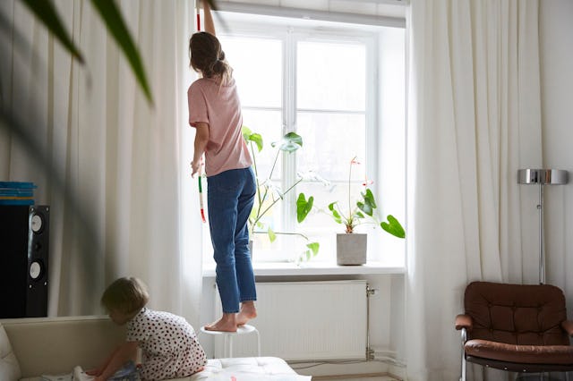 A woman measures curtains.