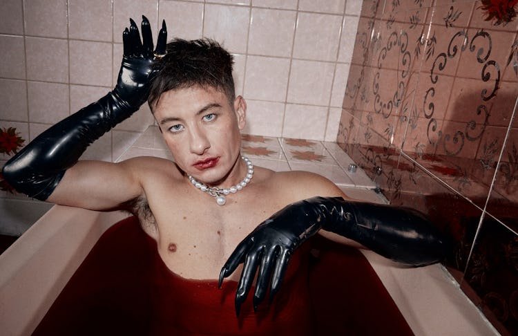 Actor Barry Keoghan sitting in a bathtub wearing a pearl necklace, long black leather gloves and red...