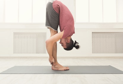 A man in standing forward bend pose.