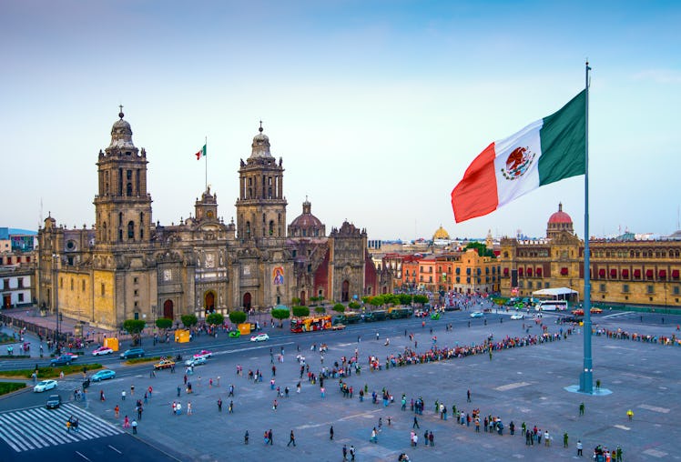 The Mexican flag flies over the Zocalo, the main square in Mexico City. The Metropolitan Cathedral f...