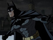 Animated Batman stands ready on a rooftop at night with a city skyline in the background.