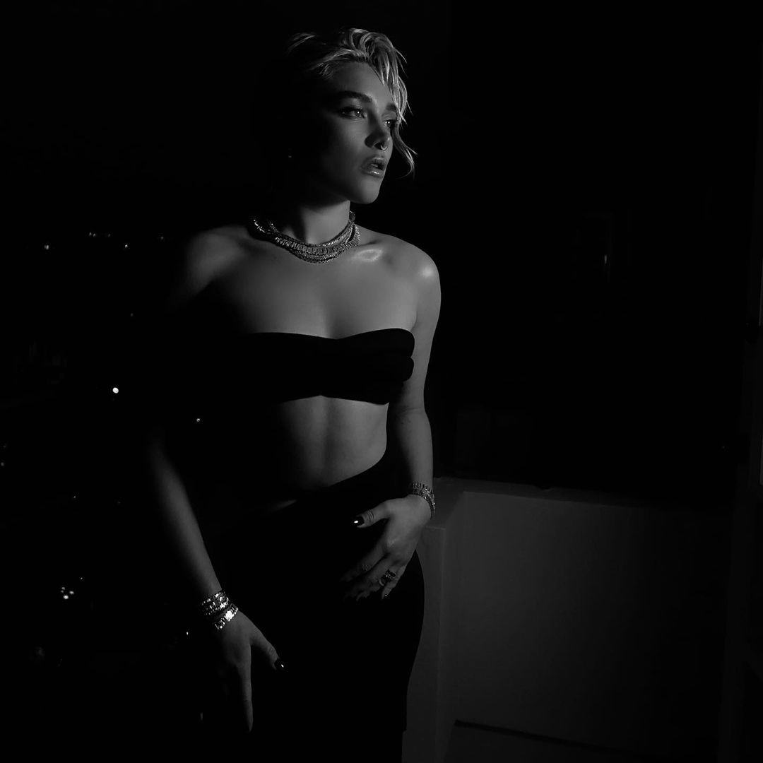 Florence Pugh wears a bandeau bra as a top and black maxi skirt.