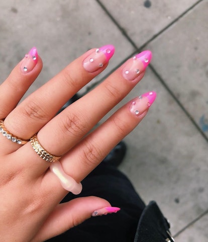 Pink French tip nails with rhinestone studs are on-trend for 2024.