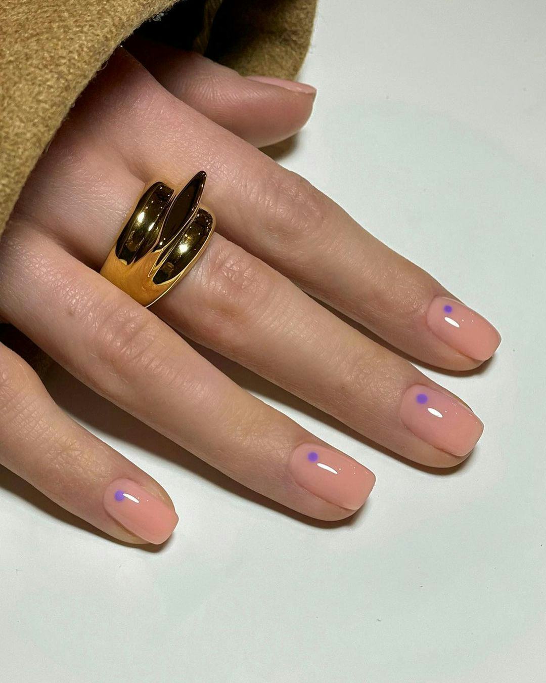 Purple dot designs on neutral nails are on-trend.
