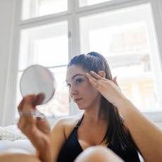 A woman looks at her undereye area.