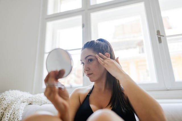 A woman looks at her undereye area.