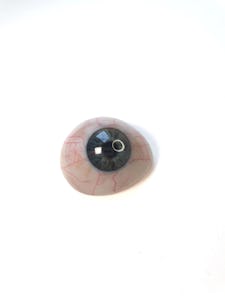 A prosthetic eye with detailed iris and red veins against a white background.
