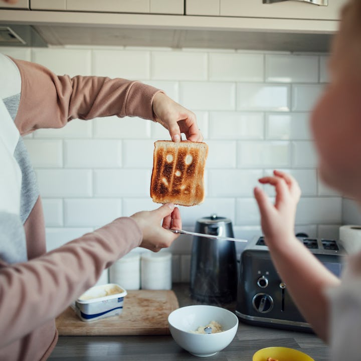 A woman holds up a piece of burnt toast to show her son.