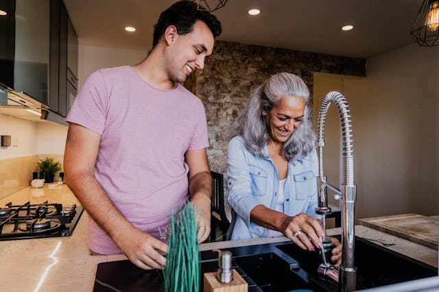 A mother and her adult son talk in the kitchen.