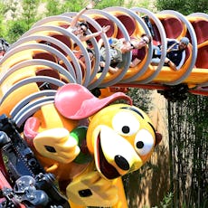 Guests at Disney World ride the Slinky Dog Dash rollercoaster, some of them raising their hands in e...
