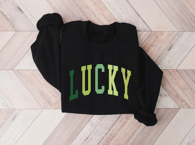 Black sweatshirt that says lucky in green writing, a casual St. Patrick's Day outfit for women.