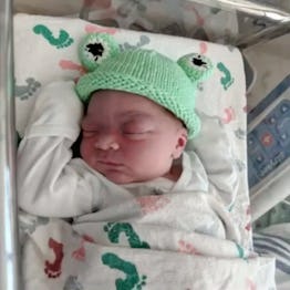 A baby born on Leap Day wears a frog hat.