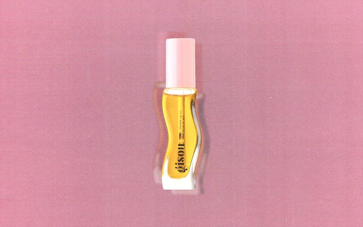 A tube of Gisou's honey-infused lip oil against a pink background
