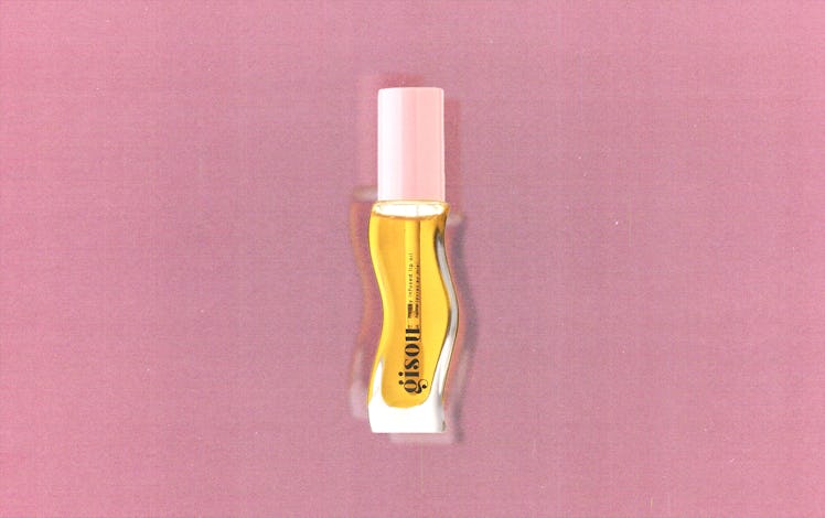 A tube of Gisou's honey-infused lip oil against a pink background
