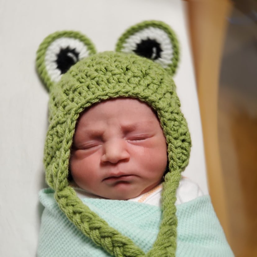 A baby born on Leap Day wearing a frog hat.