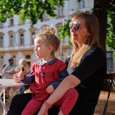 A mother sits at an outdoor cafe in Prague with her kids.