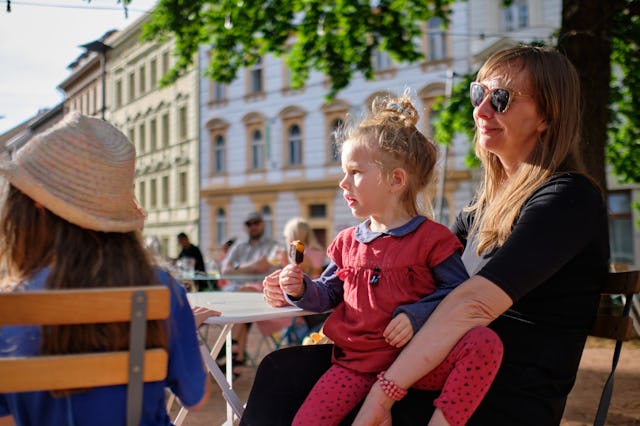 A mother sits at an outdoor cafe in Prague with her kids.