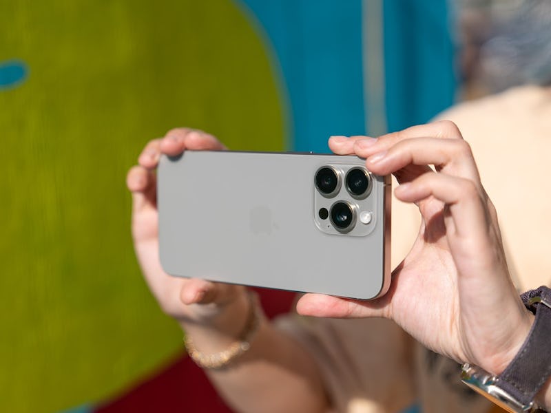 Hands holding iPhone 15 in landscape.