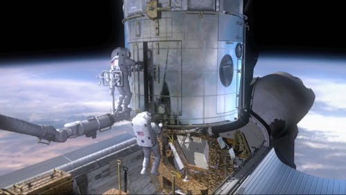 Two American astronauts work on a capsule orbiting earth.