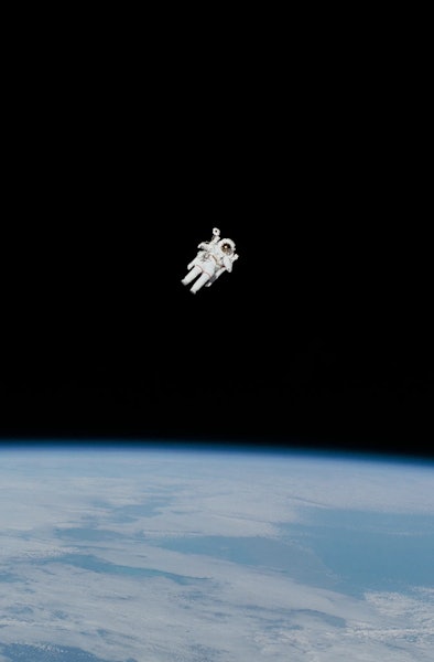 An astronaut flies above the Earth. The astronaut is at a great distance from the viewer, and no cab...