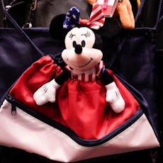 A Minnie Mouse toy hangs on the back of a wheelchair.